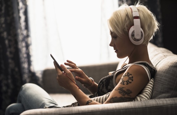 Woman sitting on sofa using digital tablet.