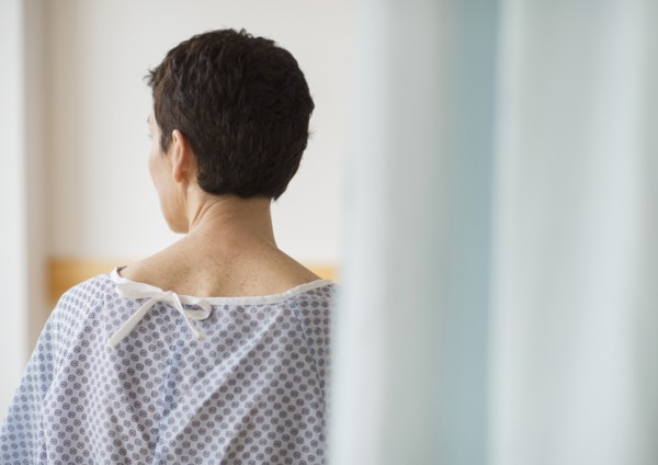 Rear view of senior woman wearing hospital gown.