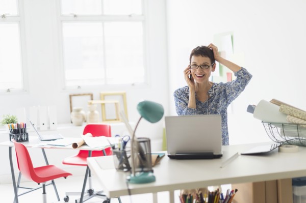 Senior business woman using cell phone in office.