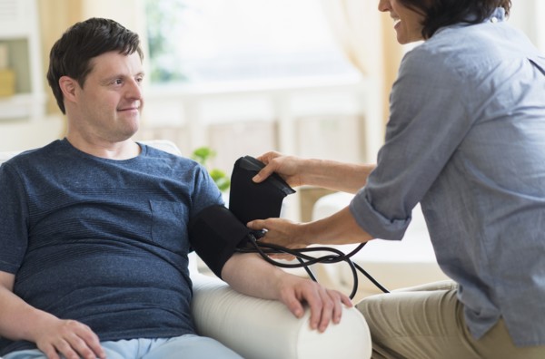 Man with down syndrome having blood pressure measured.