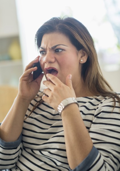 Surprised woman sitting on sofa with mobile phone.