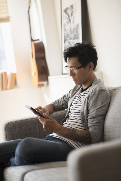 Man sitting on sofa and using tablet.