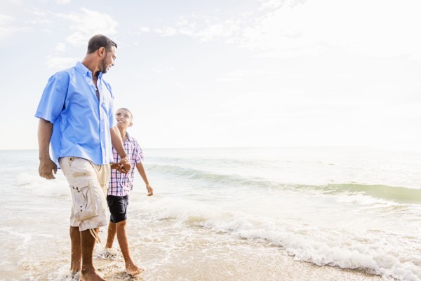 Father and son (10-11) walking on beach