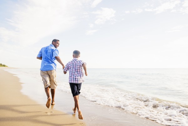 Father and son (10-11) running on beach