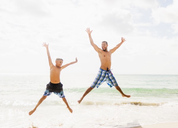 Father and son (10-11) having fun on beach