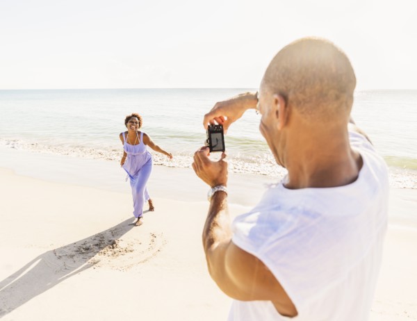 Man photographing woman on beach