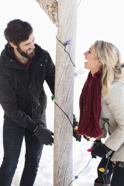 Young couple decorating house with christmas lights