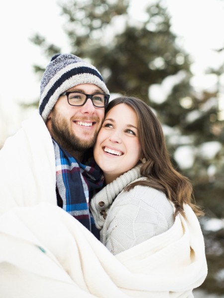 Portrait of couple wrapped in blanket smiling outdoors