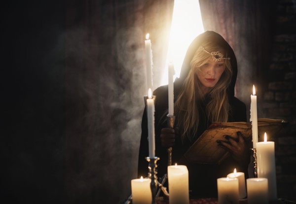 Sorceress reading book in dark room.