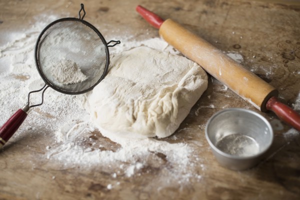 Rolling pin, Strainer and dough on kitchen counter.