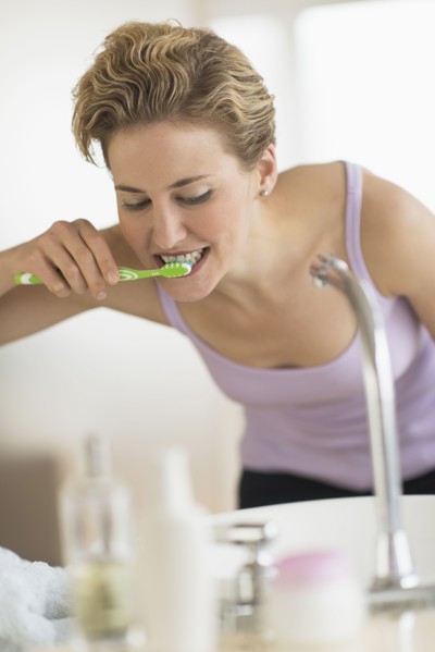 Young woman brushing teeth in bathroom.