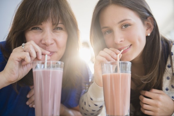 Portrait of mother and daughter (14-15) drinking milkshakes