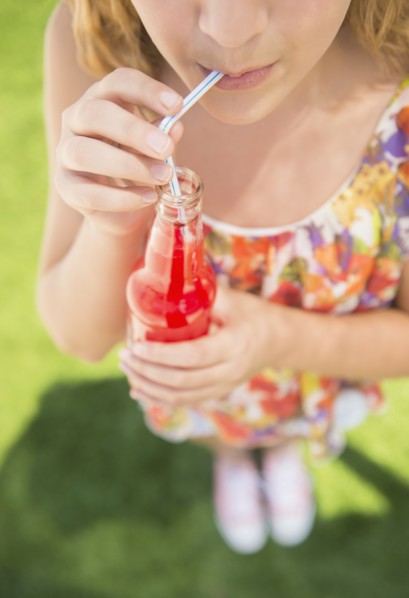 Girl (12-13) drinking soda from bottle using straw