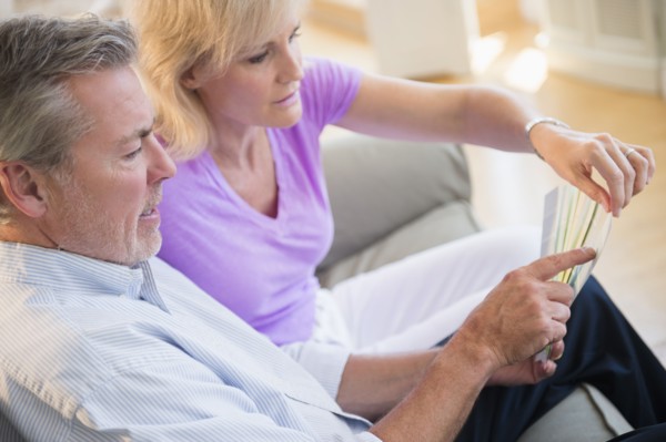 Portrait of couple sitting on sofa looking at sheet of paper