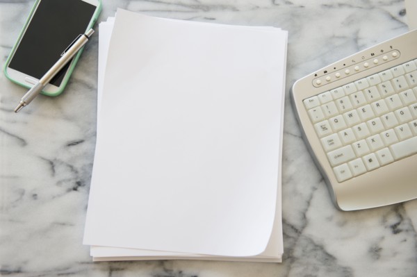 Studio shot of smart phone, sheets of paper, pen and computer keyboard