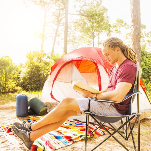 Man reading book in front of tent