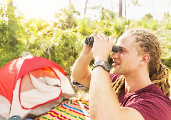 Young man watching birds through binoculars