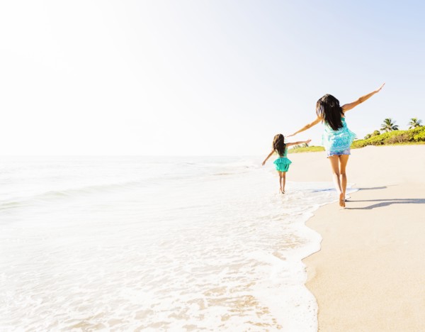 Rear view of girl (6-7) and her mom running on beach