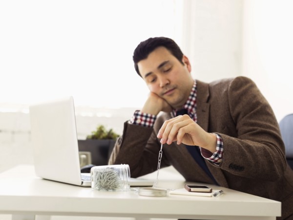 Businessman sitting in office and playing with paper clips