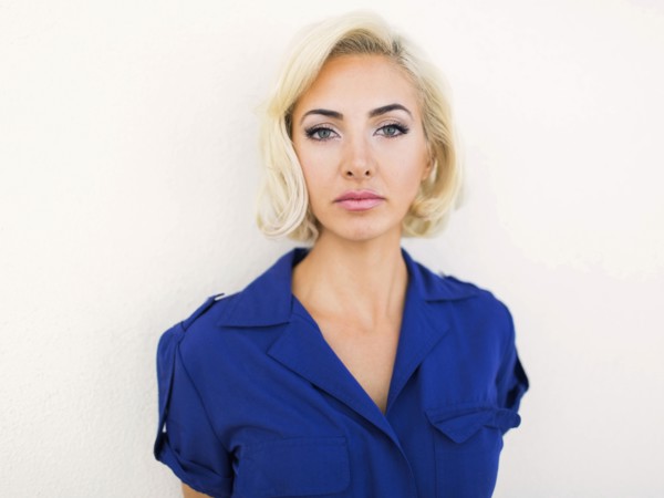 Woman in blue dress posing to camera against white background