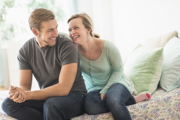 Smiling couple sitting on bed.