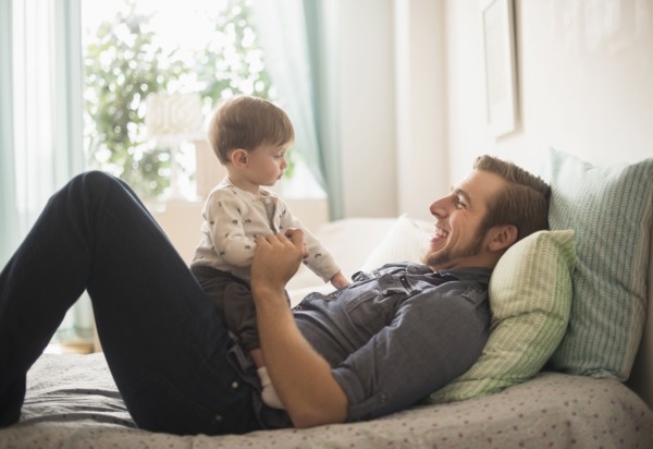 Happy father playing with little son (2-3 years) on bed.
