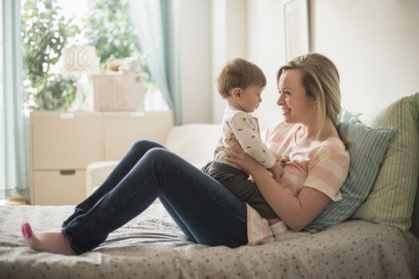 Happy mother playing with little son (2-3 years) on bed.