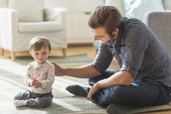 Father sitting on floor with little son (2-3 years).