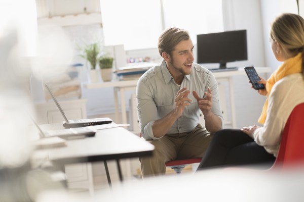 Young man and woman discussing at desk in office.