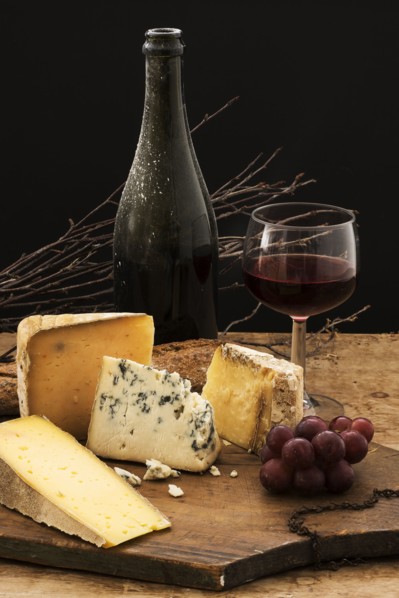Still life with cheese and red wine on wooden table, studio shot.