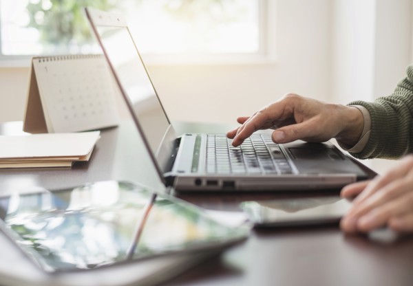 Close up of man's hands using laptop at desk.