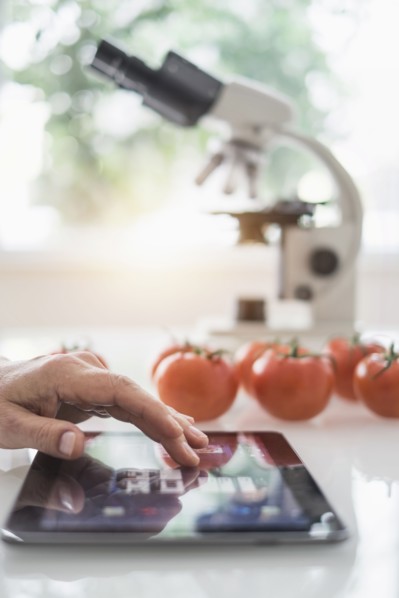 Close up of man's hand using digital tablet in laboratory.