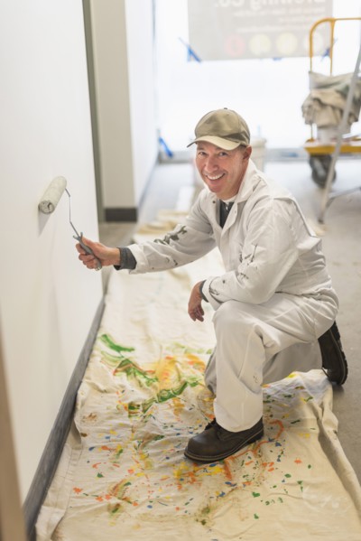 Portrait of smiling manual worker painting wall.
