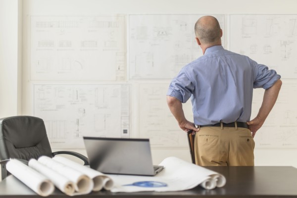 Mature architect looking at blueprints in office.