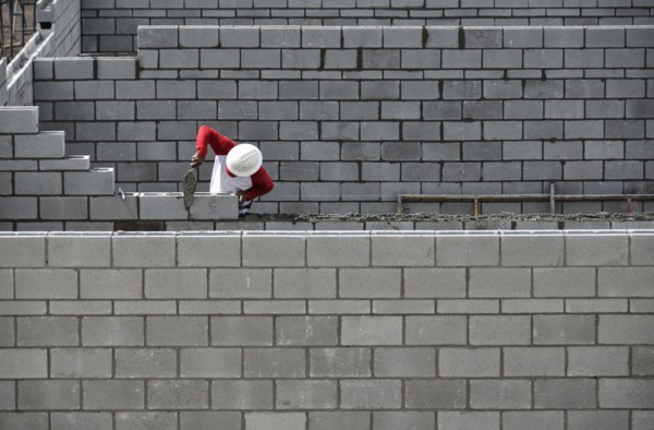 Bricklayer working on brick wall.