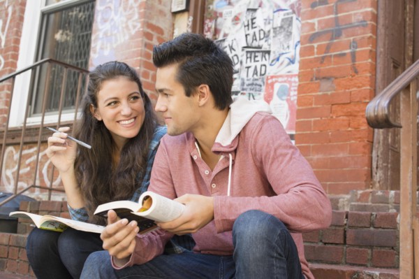 Young couple reading book and doing crossword
