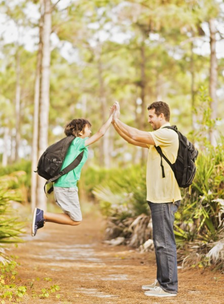 Father and son (12-13) doing high five in forest