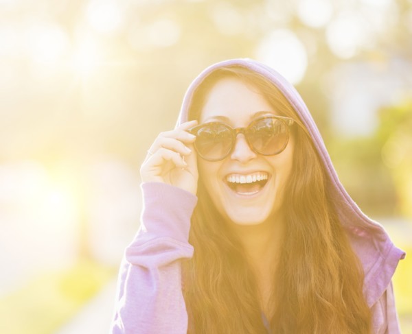 Portrait of smiling woman in hoodie with sunglasses