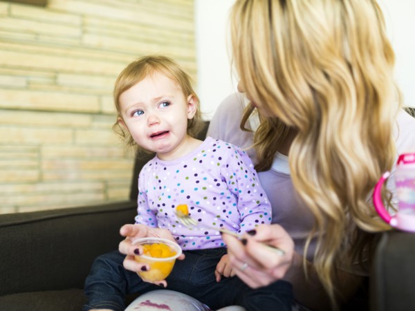 Woman feeding her daughter (12-17 months)