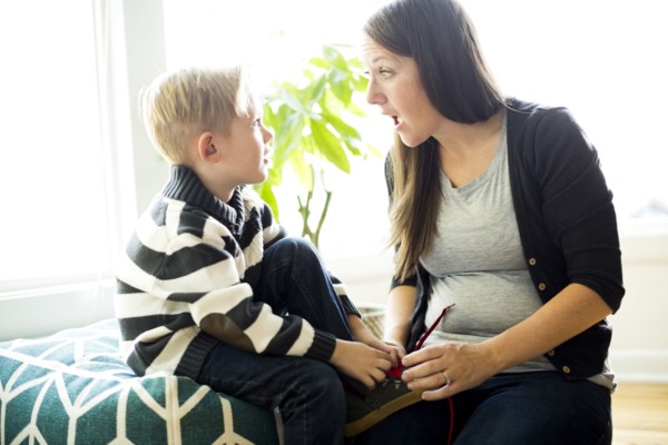 Mother helping son (6-7) putting shoe on