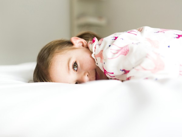 Girl (2-3) lying on bed