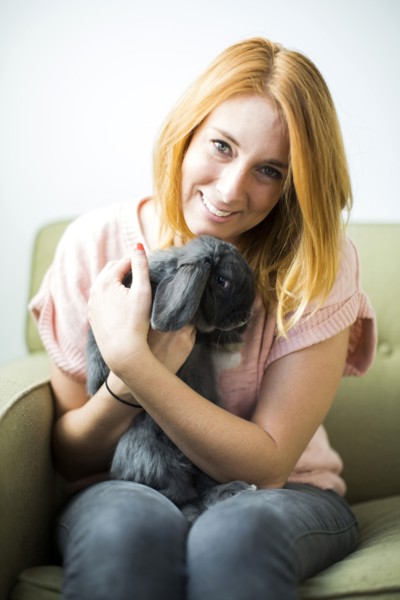 Woman sitting on sofa embracing rabbit