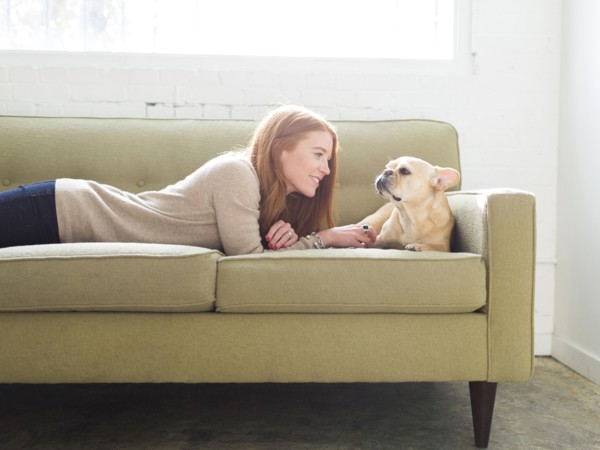 Woman and pug lying on sofa