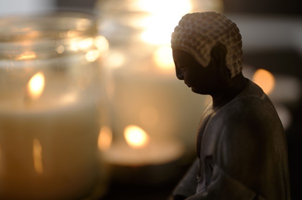 Burning candles with Buddha figurine in foreground.