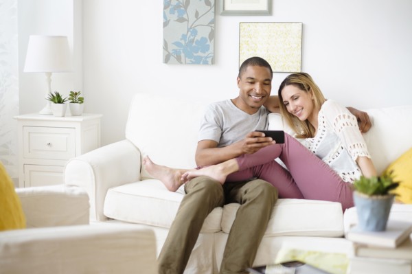 Mid adult couple looking at smart phone in living room.