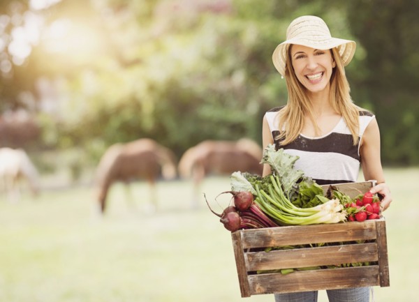 Woman carrying fresh vegetables in box.