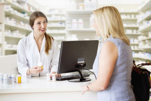 Patient talking to pharmacist in pharmacy.