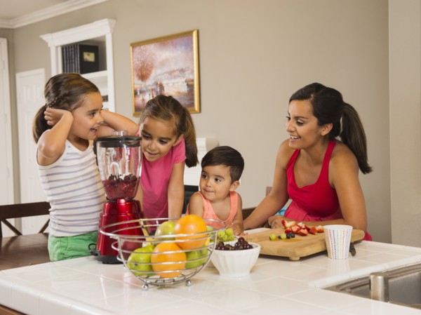 Mother and children (2-3, 6-7, 8-9) preparing fruit cocktails