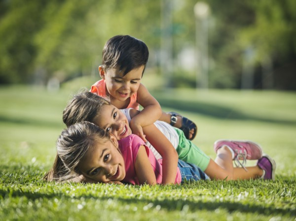 Children (2-3, 6-7, 8-9) playing in park