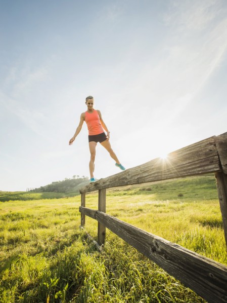 Woman balancing on wooden fence